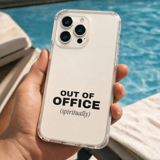 Clear iPhone case printed “Out of office (spiritually)” in black, held by a pool