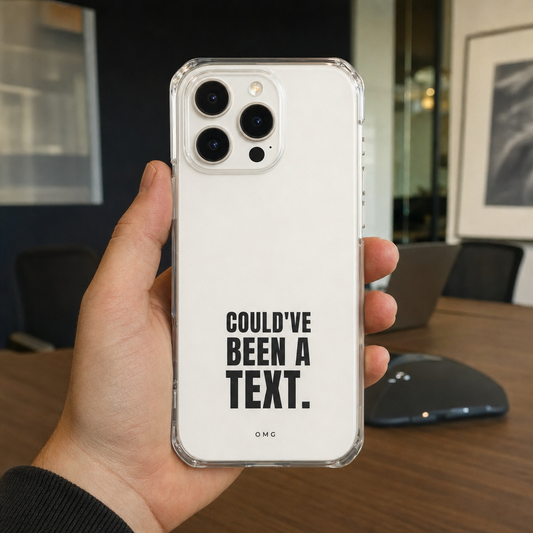 Clear iPhone case printed “Could’ve been a text.” in black, held up in a meeting room