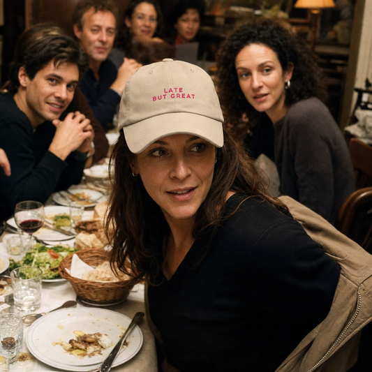 Late But Great embroidered classic cap in stone, worn arriving late to a restaurant table